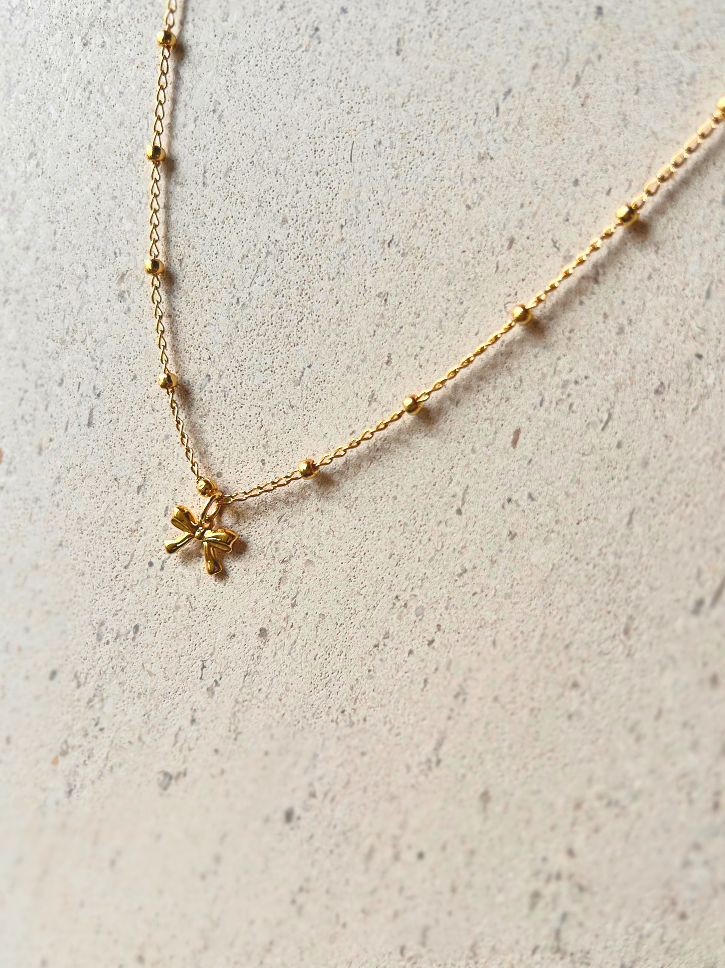 Choker con lazo en oro laminado (gold filled) 18K. Delicado y duradero, con estilo coquette para un toque femenino y juguetón. Collar corto ajustable con dije. Cadena con cuentas, tipo satélite. Regalo romántico para ella, Trópico Jewelry