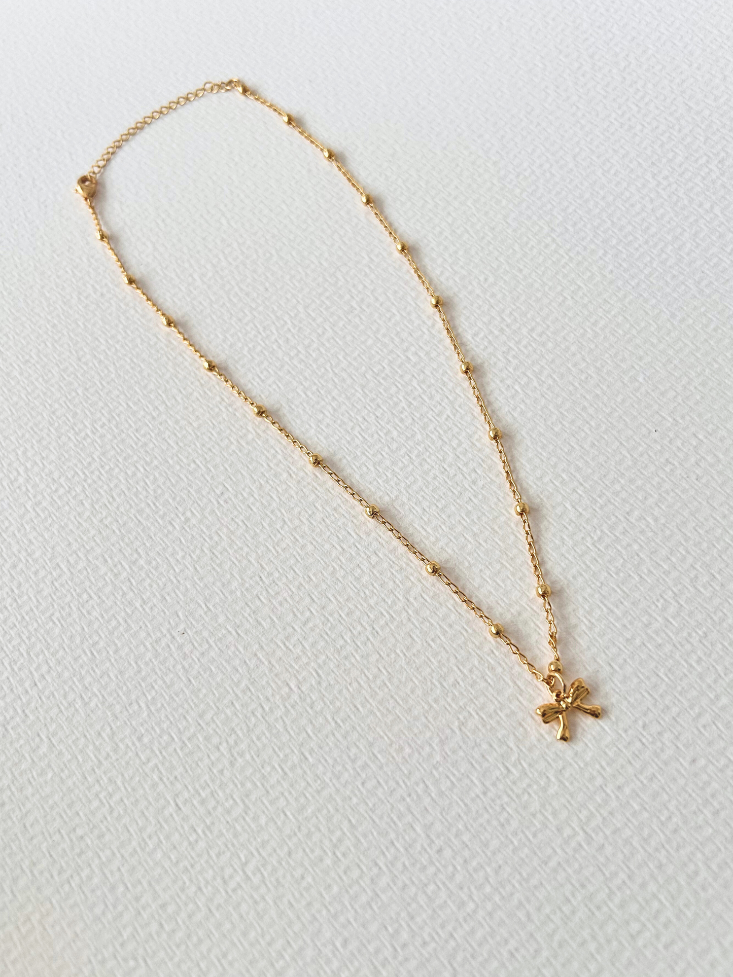 Choker con lazo en oro laminado (gold filled) 18K. Delicado y duradero, con estilo coquette para un toque femenino y juguetón. Collar corto ajustable con dije. Cadena con cuentas, tipo satélite. Regalo romántico para ella, Trópico Jewelry