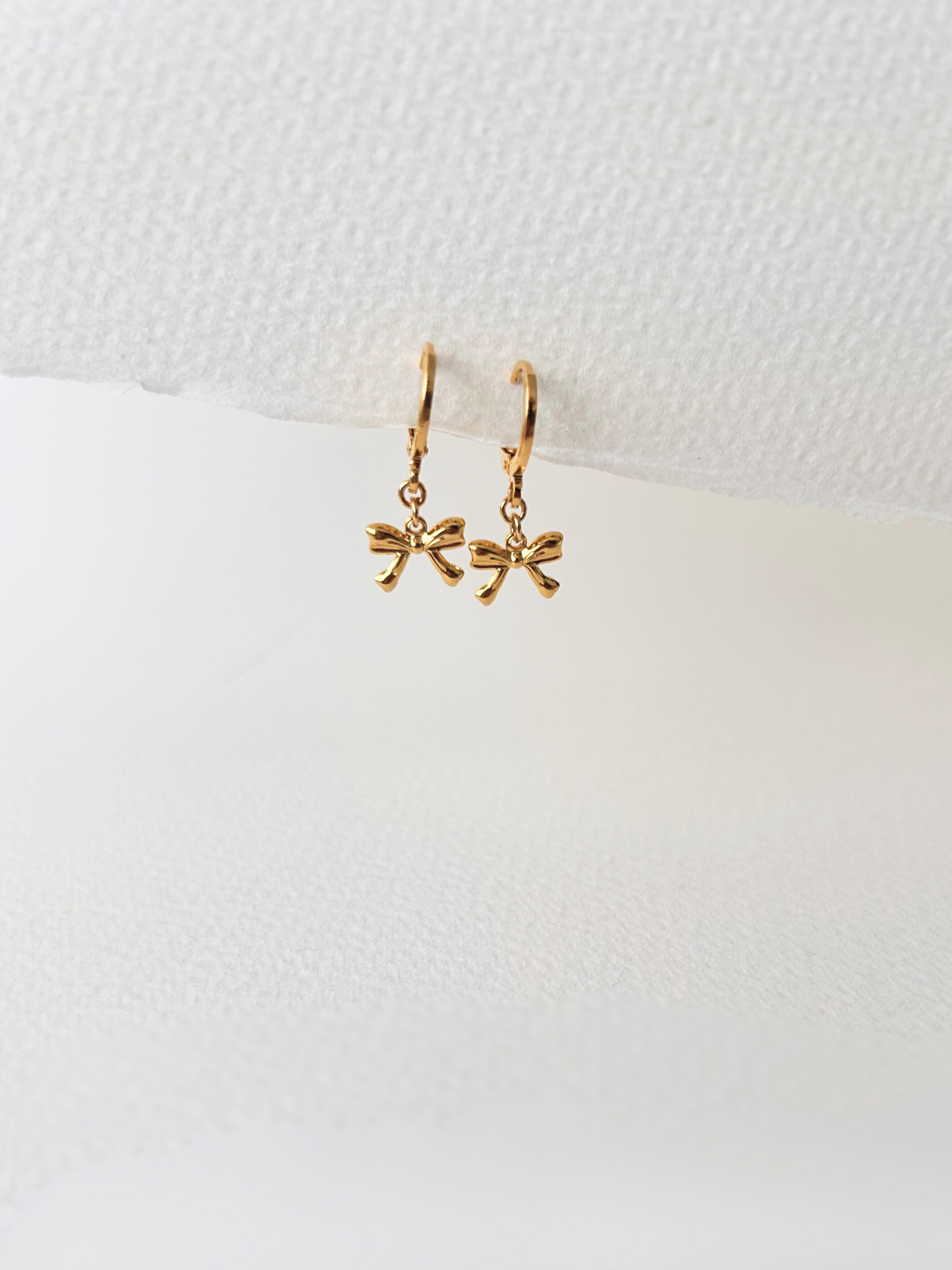 Pendientes de argollas con lazos en oro laminado 18K (gold filled). De estilo coquette, son muy femeninos y favorecedores. Duraderos, resistentes al agua y perfectos para el uso diario. Son ideales como un regalo delicado para mujer. Trópico Jewelry.