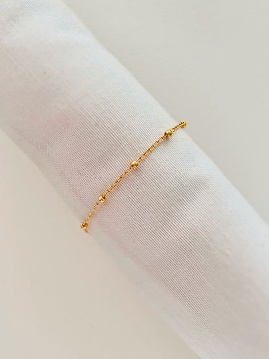 Pulsera satélite con cadena fina y bolitas, en oro laminado 18K (gold filled). Versátil, delicada y atemporal, a la vez que moderna y trendy, es un regalo perfecto. Hecha a mano en España por Trópico Jewelry.