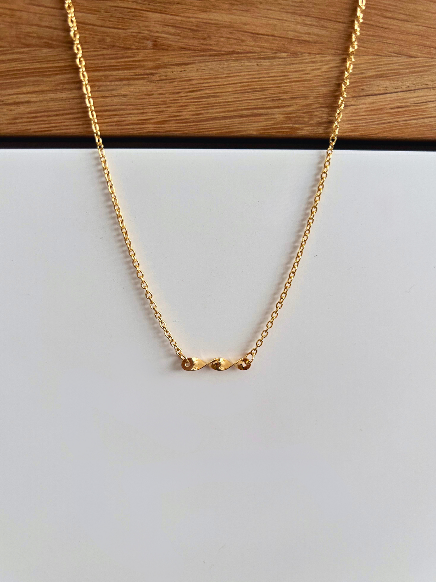 Collar delicado minimalista, chapado en oro 18K con dije geométrico retorcido estilo remolino. Regalo especial para mujer hecho a mano por Trópico Jewelry