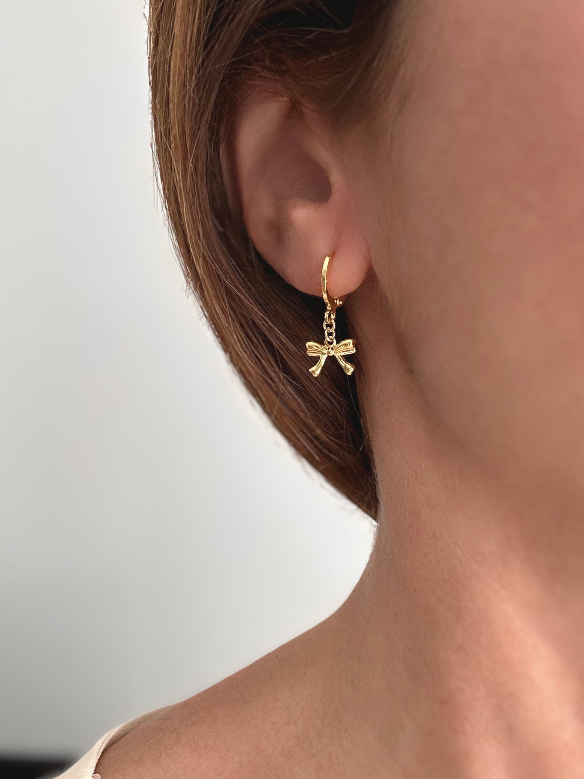 Pendientes de argollas con lazos en oro laminado 18K (gold filled). De estilo coquette, son muy femeninos y favorecedores. Duraderos, resistentes al agua y perfectos para el uso diario. Son ideales como un regalo delicado para mujer. Trópico Jewelry.