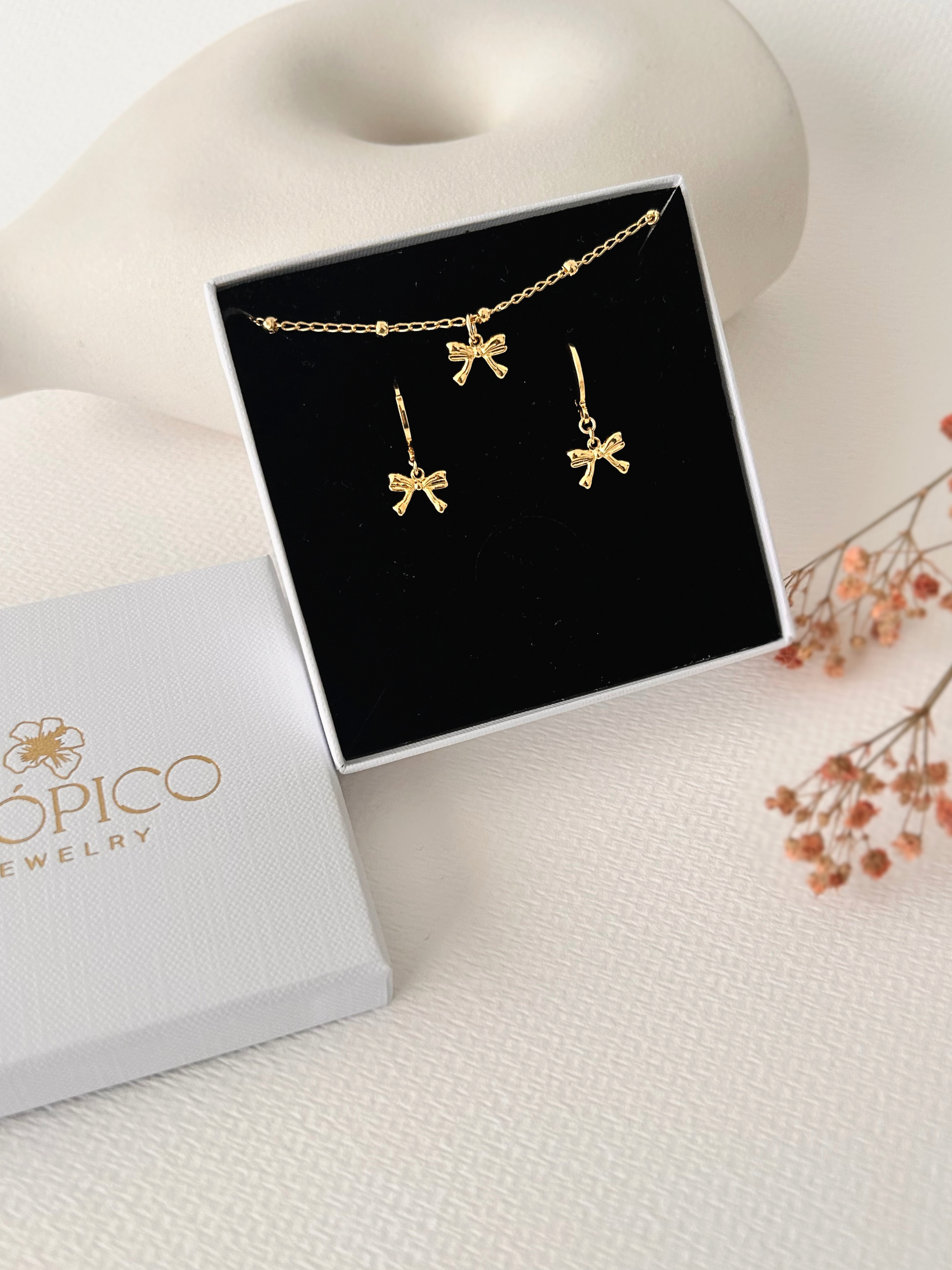 Pendientes de argollas con lazos en oro laminado 18K (gold filled). De estilo coquette, son muy femeninos y favorecedores. Duraderos, resistentes al agua y perfectos para el uso diario. Son ideales como un regalo delicado para mujer. Trópico Jewelry.